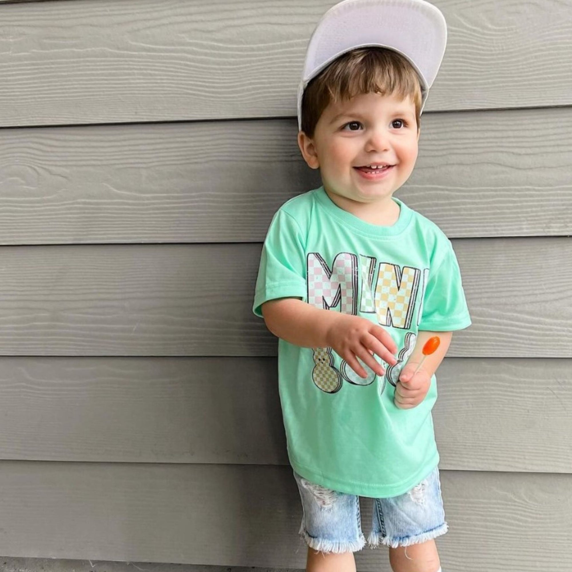 Child in green shirt with a zollipop.