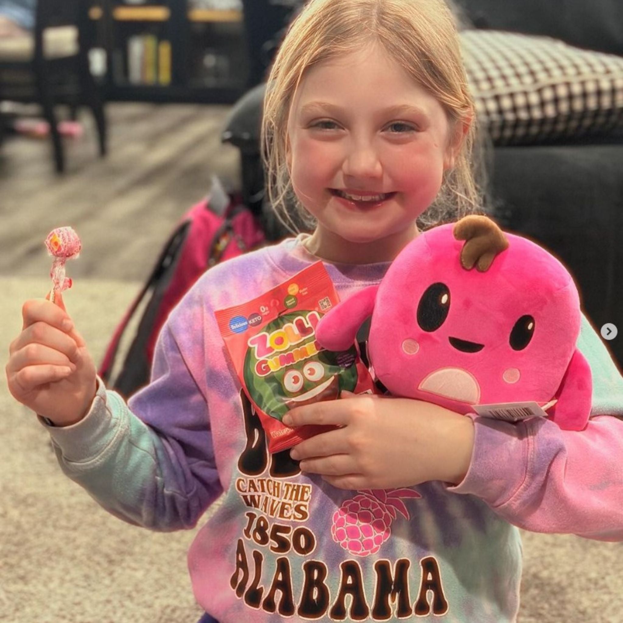 Child with watermelon gummez, a lollipop, and a plushie.