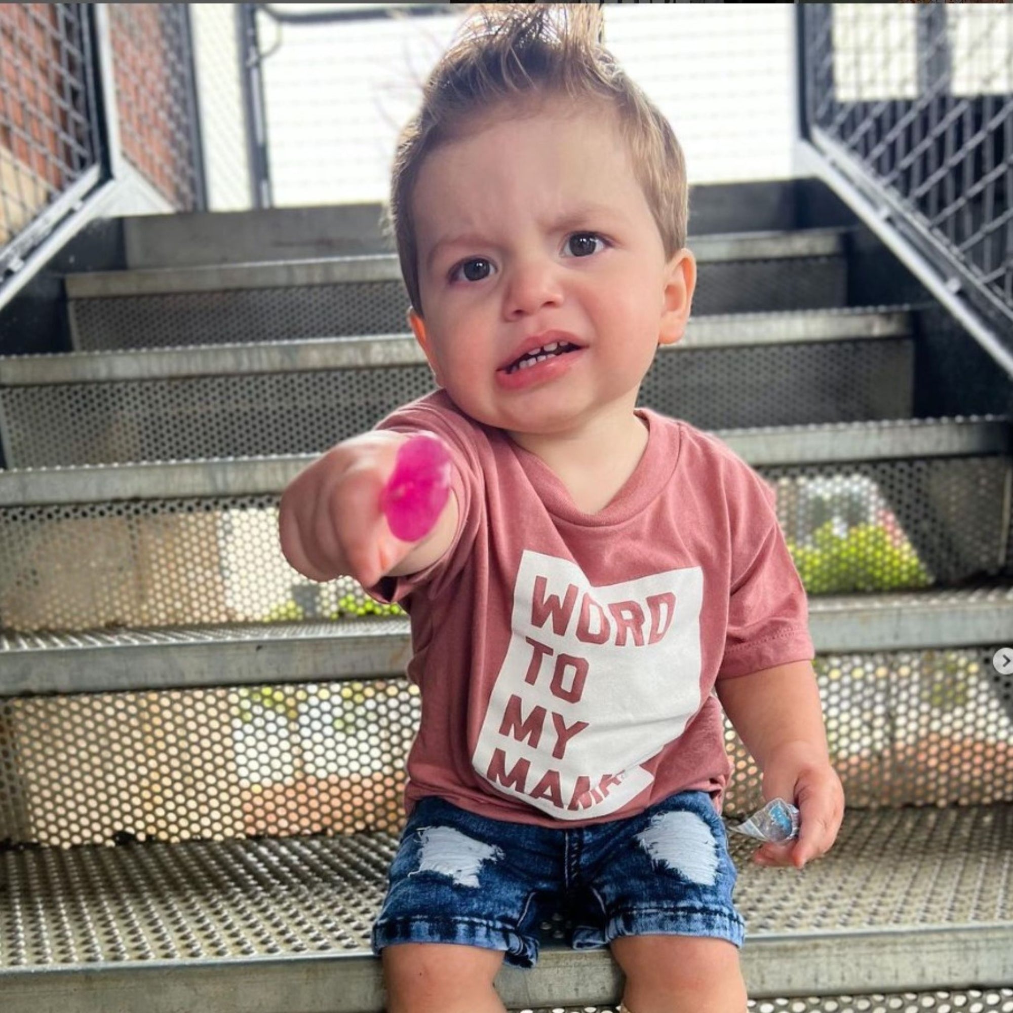 Child with zollipop sitting on steps.