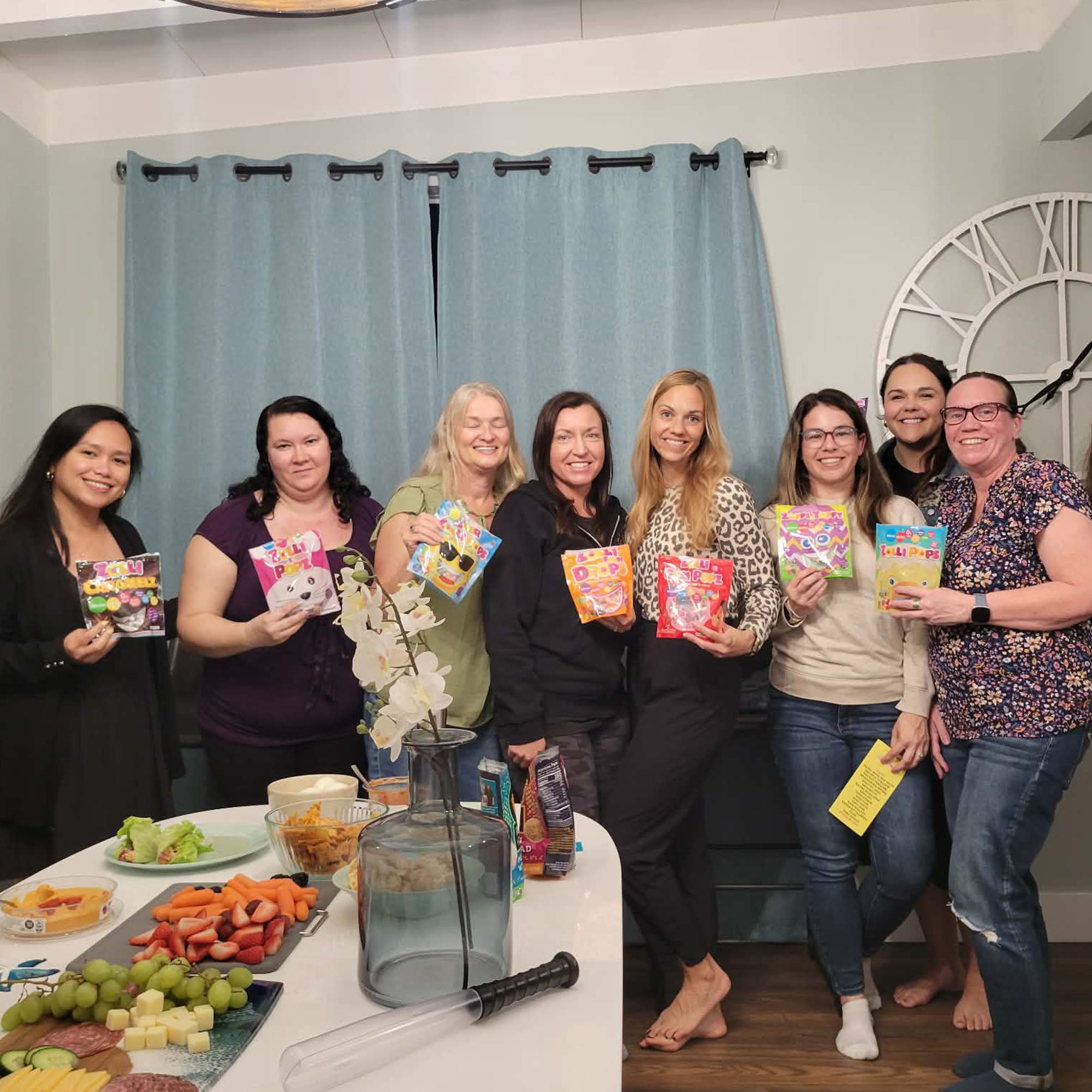 Group of women holding colorful boxes in a room with a table and decorative items.