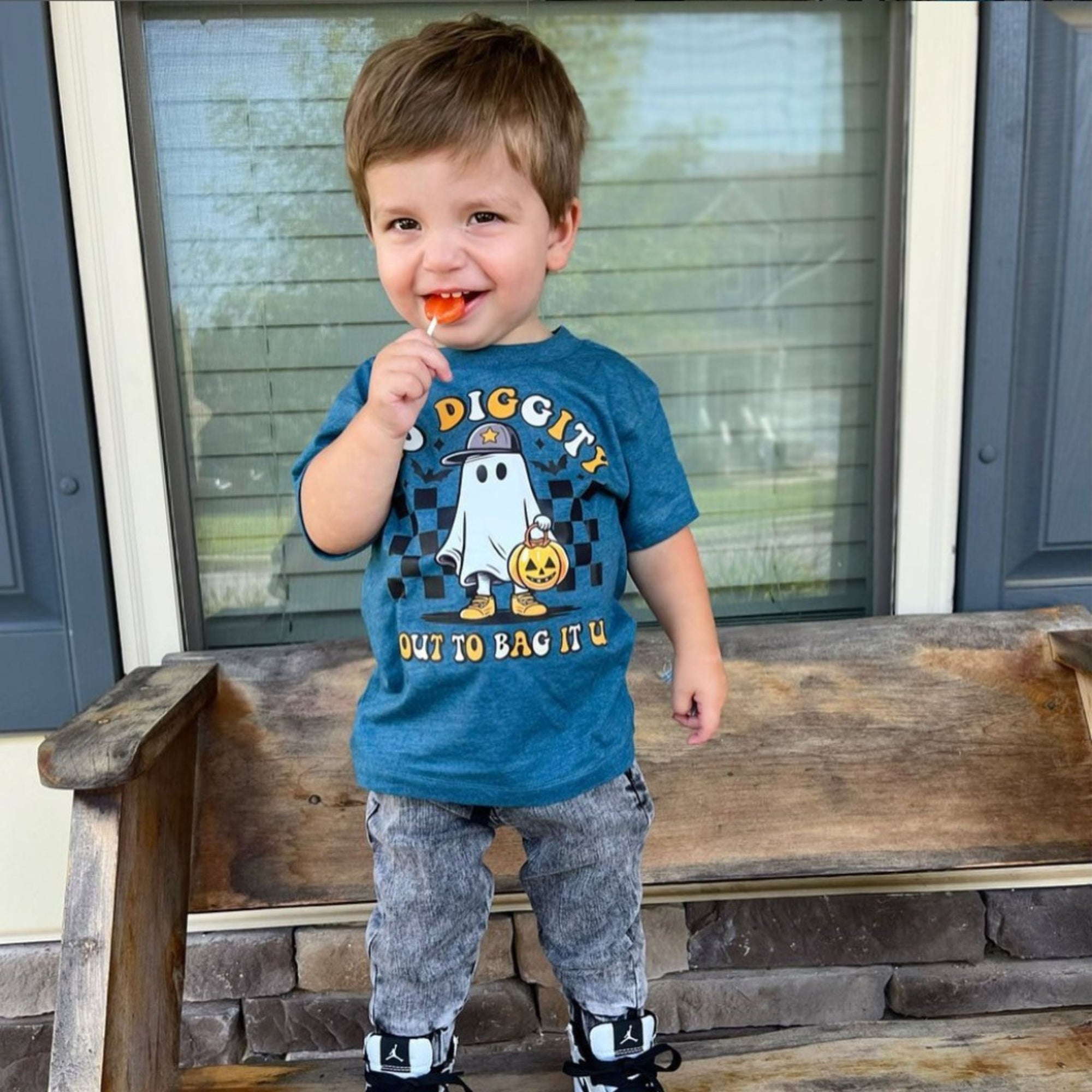 Child in a trick or treat shirt with zollipop.