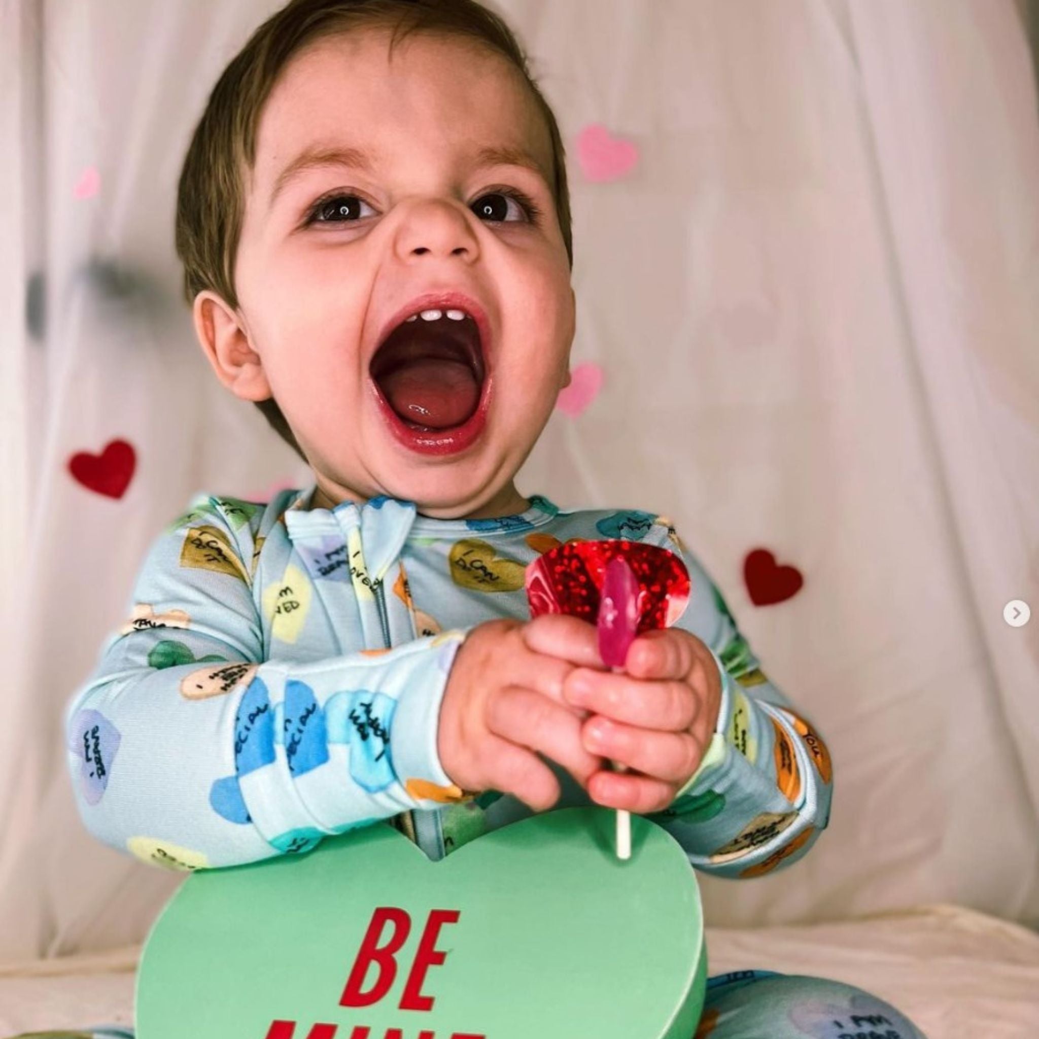 Child in valentines themed outfit with zollipop