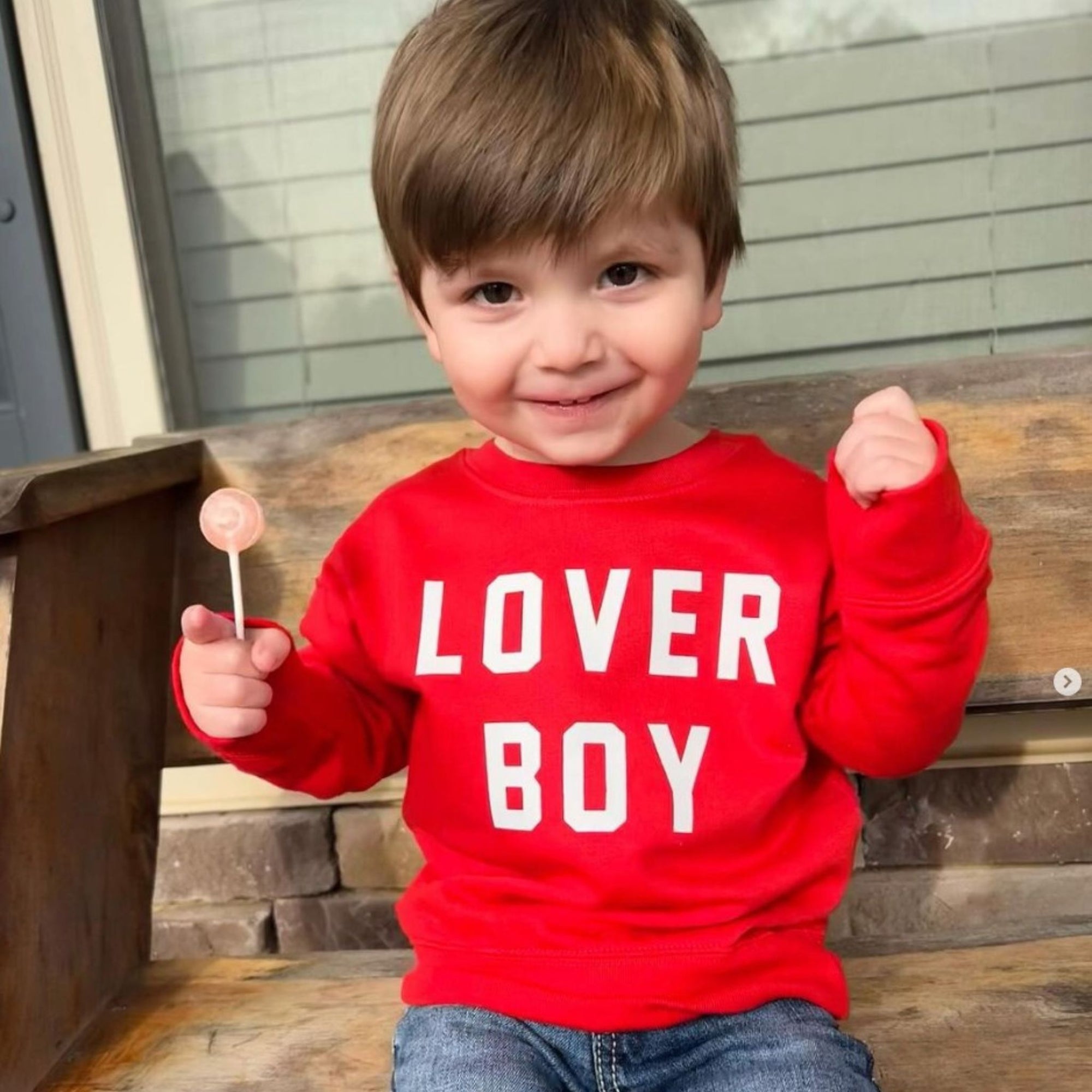 Child with red shirt and a zollipop.