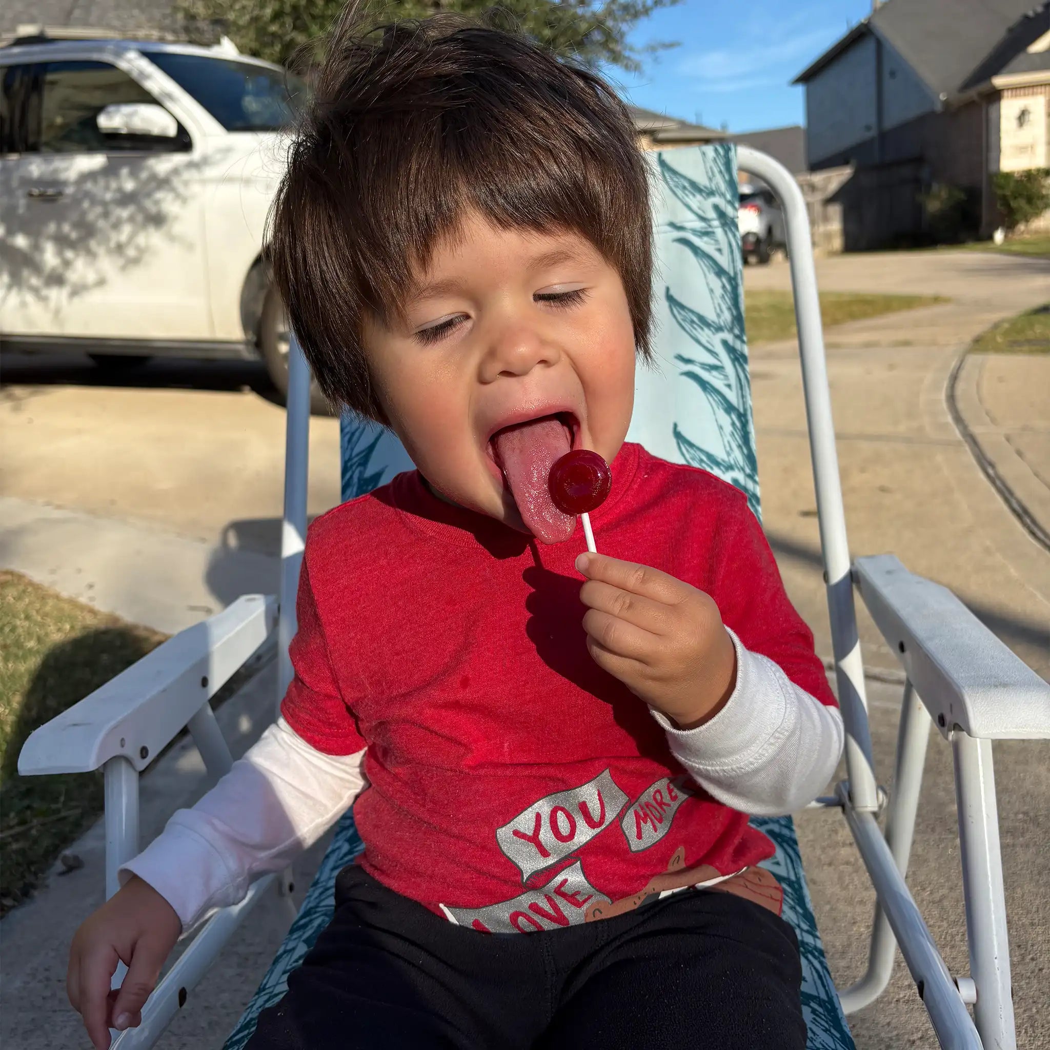 Child enjoying a zollipop outside.