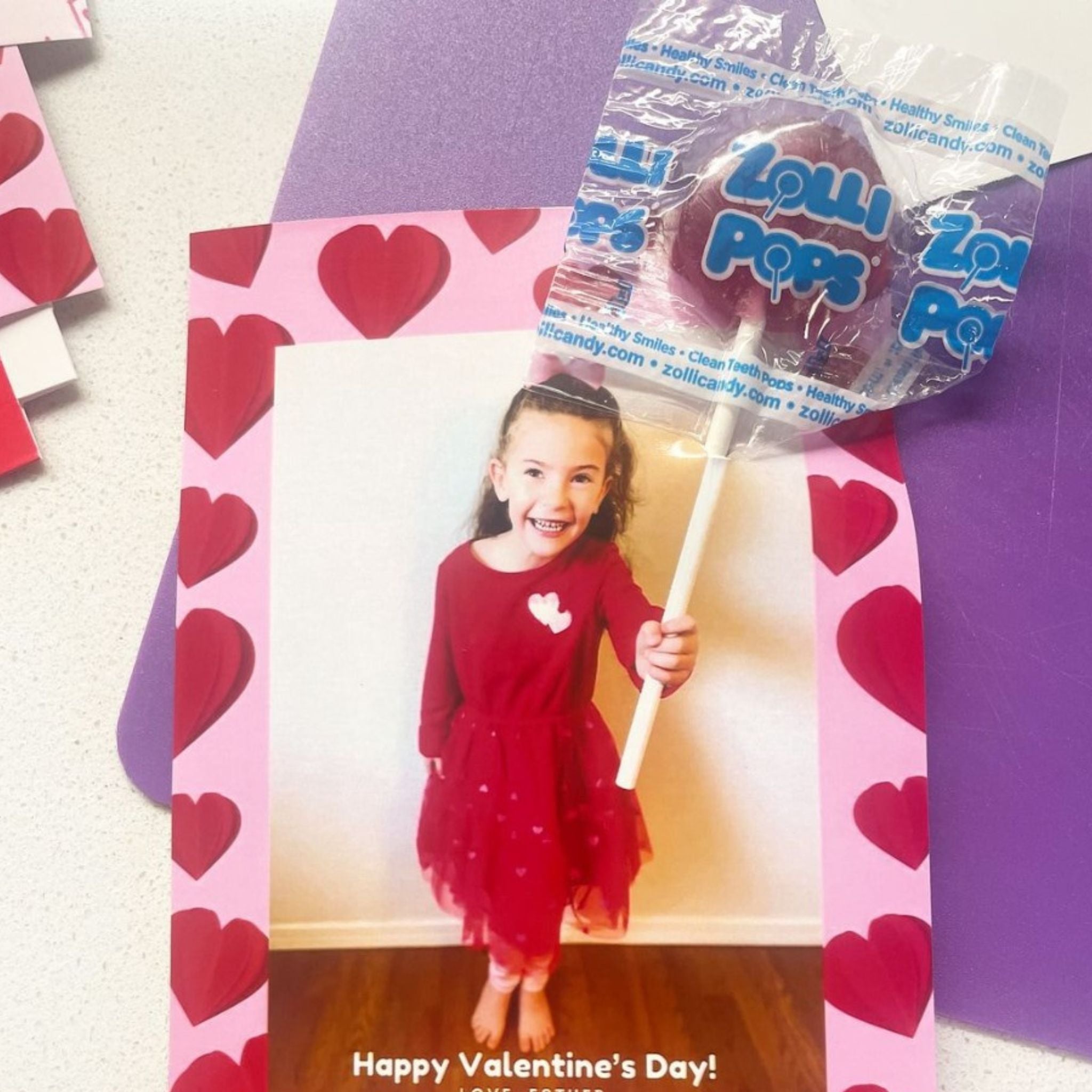 A valentine made with a picture of child holding a zollipop.